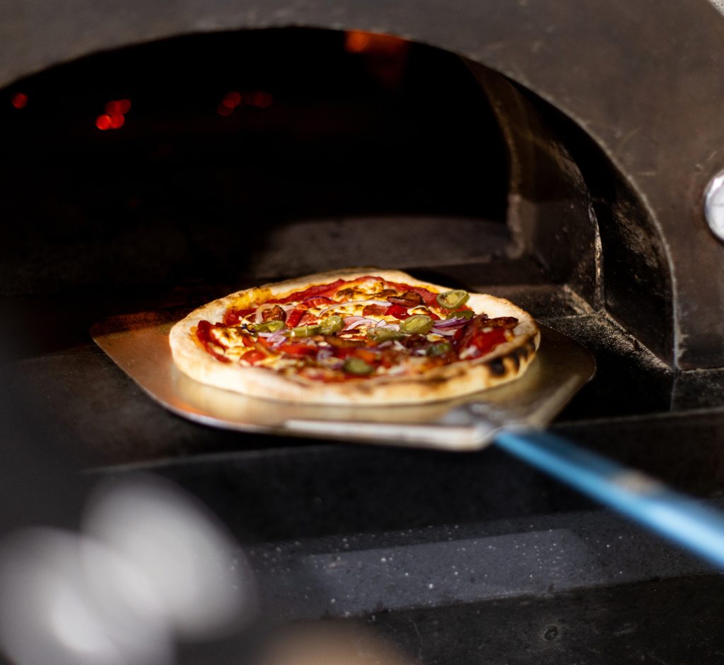Pizza coming out of the pizza oven