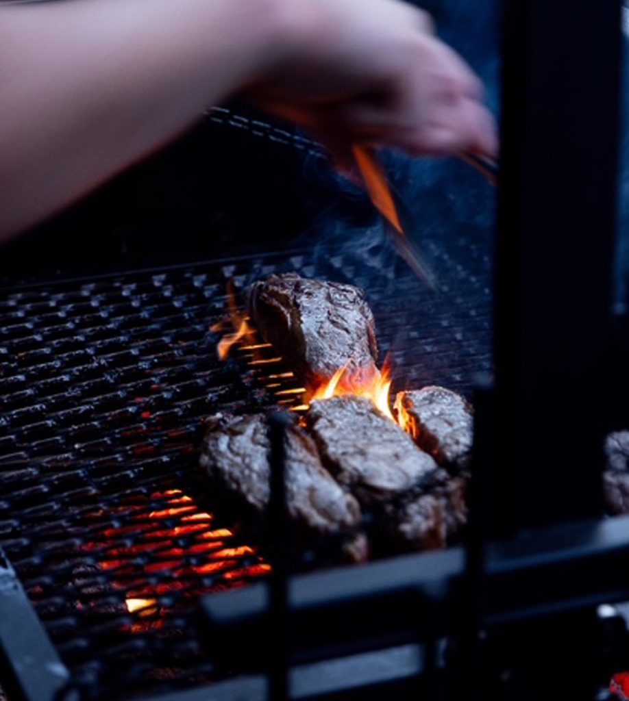 Steak being cooked on a grill with flames